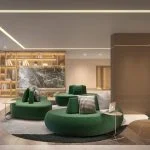 Lounge e espaço coworking do Vista Nova Carlos Gomes com sofás verdes e estante iluminada, no Petrópolis, Porto Alegre